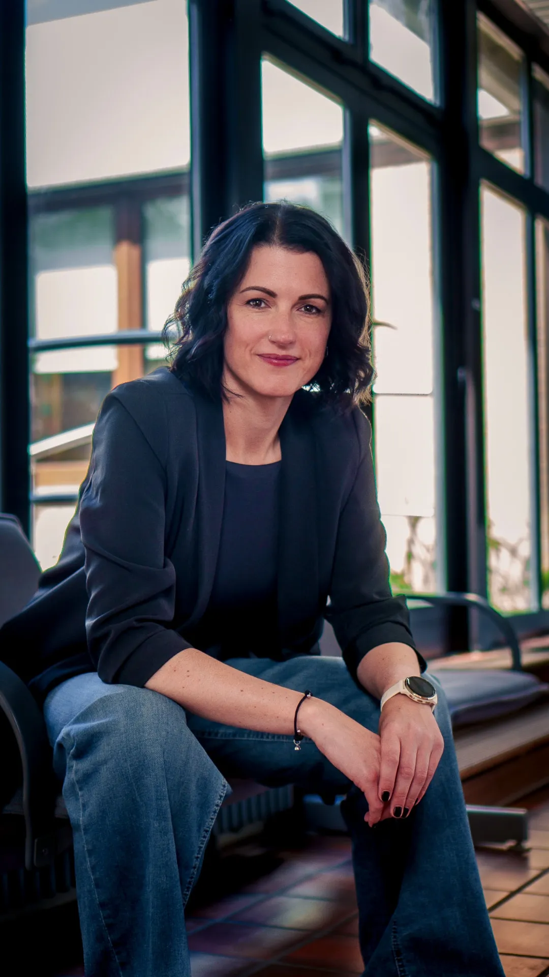 Business Portrait einer sitzenden Frau vor Fensterfront